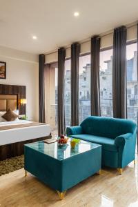a living room with a blue couch and a bed at Hotel Apple Tree - Near Mahipalpur Market in New Delhi