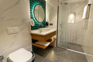 ein Badezimmer mit Waschbecken, Toilette und Spiegel in der Unterkunft Q Style Hotel in Pelitli