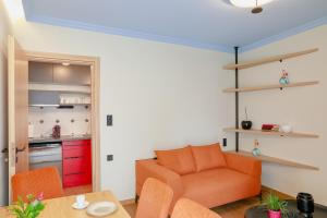 a living room with an orange couch and a kitchen at Olympia 3 in Xanthi