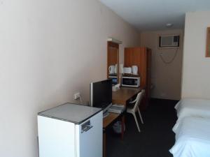 a room with a desk with a computer and a bed at Jasper Motor Inn in Adelaide