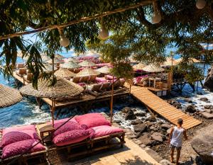 a man standing on a beach with chairs and umbrellas at Assos Plus in Ayvacık
