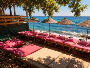 a row of beach chairs with umbrellas on the beach at Assos Plus in Ayvacık +5 photos