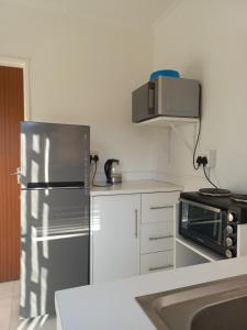 a kitchen with a stainless steel refrigerator and a microwave at Sintha guest house in Kraaifontein