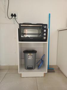 a microwave sitting on top of a shelf with a trash can at Sintha guest house in Kraaifontein