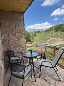 a patio with chairs and a table and a stone wall at Durmitor Family Escape Žabljak in Borje
