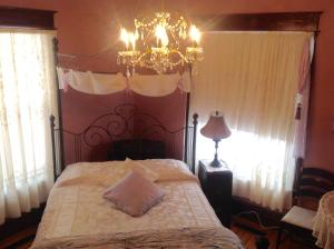 a bedroom with a bed with a chandelier and windows at Maison McKenzie House in Campbellton