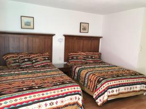 two beds in a hotel room with two beds at Apache Motel in Ruidoso