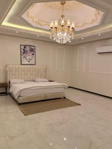 a bedroom with a large bed and a chandelier at شاليهات Luma الفندقية in Bisha Airport +91 photos
