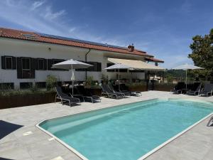 a swimming pool with chairs and umbrellas next to a house at Casa Alba Blu in Dogliani