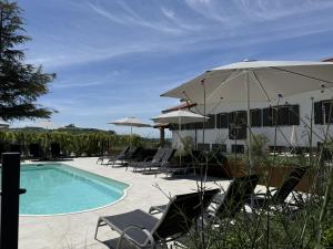 a pool with chairs and umbrellas next to a house at Casa Alba Blu in Dogliani