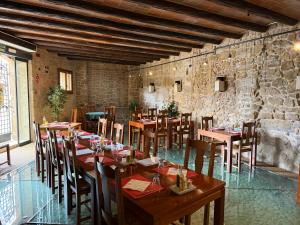 a restaurant with wooden tables and chairs and a stone wall at HOTEL EL CASTELL in Valderrobres