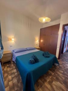 a bedroom with a blue bed with towels on it at APPARTAMENTI BIANCANEVE by VILLA AUREA CAV in Costa Rei