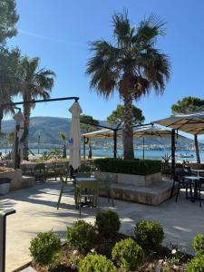 a patio with tables and umbrellas and palm trees at Hotel Bologna in Vlorë