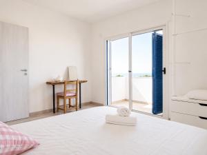 a white bedroom with a bed and a desk at Apartamentos Es Cupina in La Mola