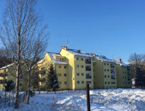 ein gelbes Gebäude mit Schnee davor in der Unterkunft Apartament Melisa in Szklarska Poręba