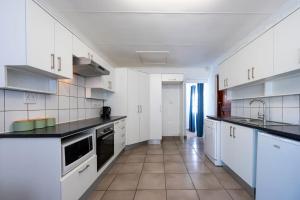 a kitchen with white cabinets and a tile floor at St Rand Holiday House in Strand