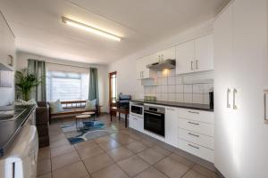 a kitchen with white cabinets and a living room at St Rand Holiday House in Strand
