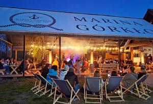 a group of people sitting in lawn chairs in front of a mannan gourmet at Marina Górkło - Żurawi Kąt in Górkło