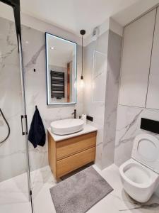 a bathroom with a toilet and a sink and a mirror at Apartament Ryżowa 66B in Warsaw