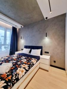 a bedroom with a large bed with a floral blanket at Apartament Ryżowa 66B in Warsaw