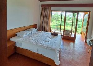 a bedroom with a large bed with a large window at Rinjani Vibe Bungalows in Tetebatu +114 photos