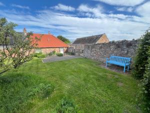 a blue bench sitting in a yard next to a stone wall at The Wee Bothy at East Lothian Cottages in Lennoxlove +9 photos
