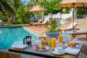 a table with breakfast foods and drinks next to a pool at The Colonial Escape in Galle