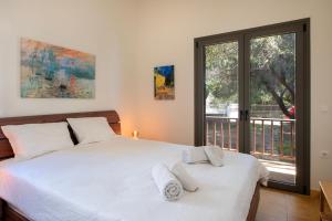 a bedroom with a bed with white sheets and a window at Villa Isabelle on the beach in Paralía Iríon