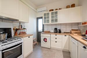 a kitchen with white cabinets and a washing machine at Villa Isabelle on the beach in Paralía Iríon