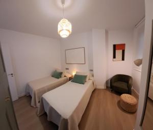 a small room with two beds and a chair at Costa Canido II in Malpica