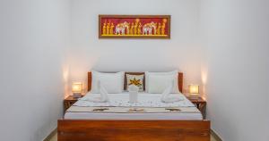 a bedroom with a bed with two lamps and a picture on the wall at Into The Wild Sigiriya in Sigiriya +47 photos