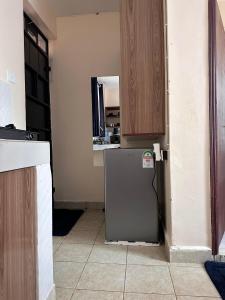 a kitchen with a refrigerator and wooden cabinets at Cool Studios, Machakos in Machakos