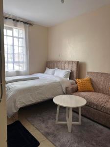 a bedroom with a bed and a couch and a table at Cool Studios, Machakos in Machakos
