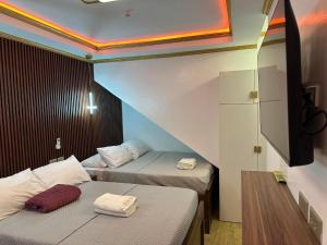 a small room with two beds and a tv at S&L Lodging House and Tampisaw Restaurant in Pandan