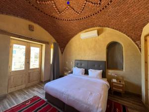 a bedroom with a large bed with a brick ceiling at Kom El Dikka Agri Lodge in ‘Izbat an Nāmūs +117 photos