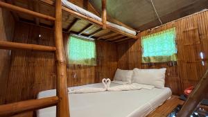 a bed in a wooden room with two towels at PAPABO Adventure Village in Moalboal
