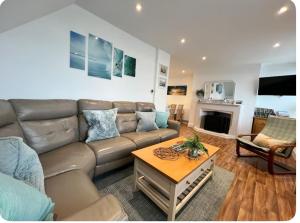 a living room with a couch and a table at Lundy Lookout 5 minutes drive to beach Hot tub in Westward Ho