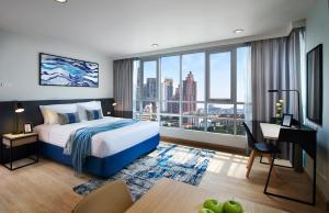 a hotel room with a bed and a desk and a window at Shama Lakeview Asoke Bangkok in Bangkok