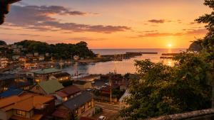 a view of a city with the sun setting over the water at ペットok 古民家ふるさと真鶴 in Manazuru