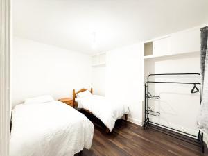 two beds in a bedroom with white walls and wood floors at Spacious 3 Bed , Free Parking , Fast WiFi , Long Stays in Kettering