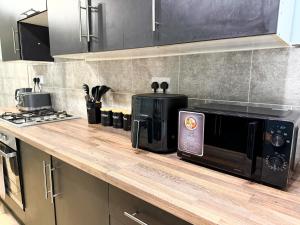 a kitchen counter with a microwave and a stove at Spacious 3 Bed , Free Parking , Fast WiFi , Long Stays in Kettering