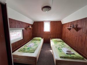 two beds in a small room with wooden walls at Keszeg house in Szigetbecse +13 photos