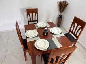 a wooden table with chairs and plates on it at Luxury résidence Bassam in Moosou +1 photo