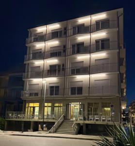 a tall white building with stairs in front of it at Hotel Margherita in Sottomarina