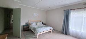 a white bedroom with a bed and a window at Storms River Family Accommodation in Stormsrivier +10 photos