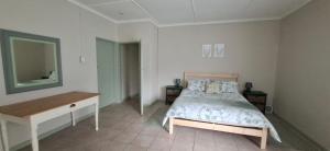 a bedroom with a bed and a dresser and a mirror at Storms River Family Accommodation in Stormsrivier