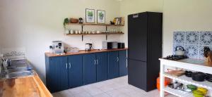 a kitchen with blue cabinets and a black refrigerator at Storms River Family Accommodation in Stormsrivier