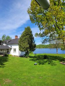 a house on a lawn with a lake in the background at Linnåsen stuga in Rottneros