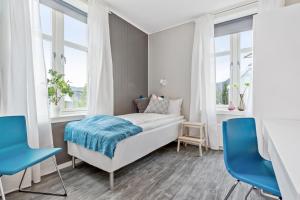 a bedroom with a bed and two blue chairs at Mogården in Orkanger