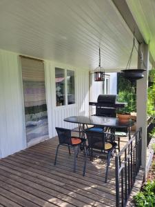 a porch with a table and chairs and a grill at Linnåsen stuga in Rottneros